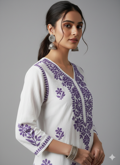 Woman wearing a white kurta with purple floral embroidery on a gray background