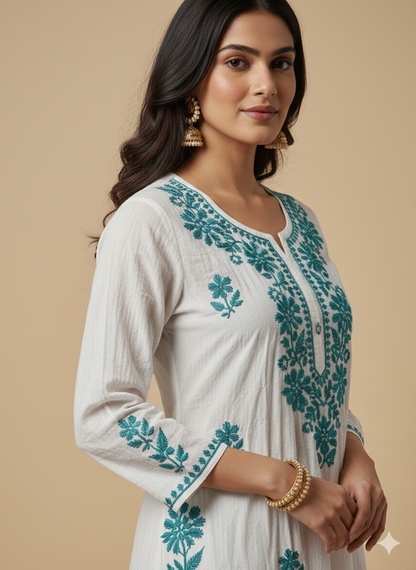 Woman wearing a white kurta with teal embroidery against a beige background
