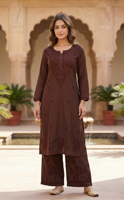 Woman wearing a brown traditional outfit in an outdoor setting with arches and plants.