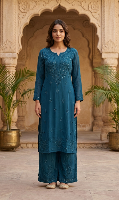 Woman in a teal traditional outfit standing in front of ornate architecture with plants.