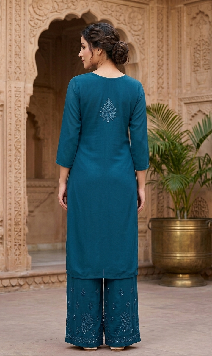 Woman wearing a teal traditional outfit with floral patterns in an ornate architectural setting.