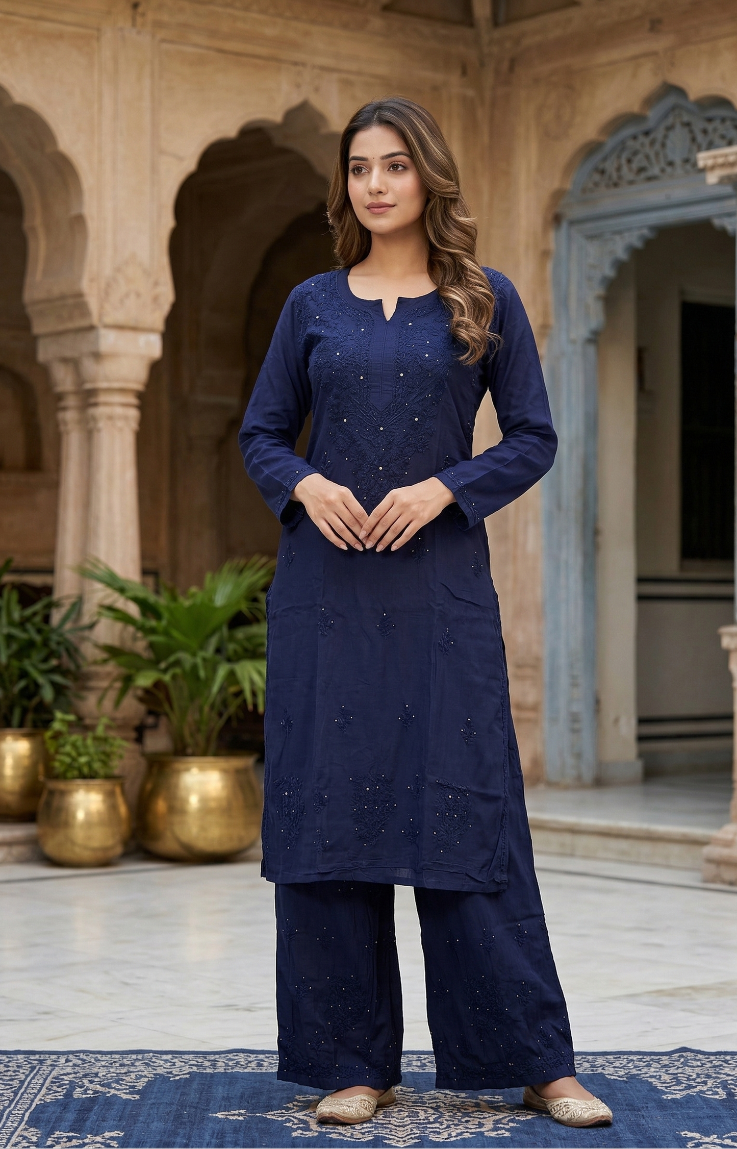 Woman in a navy blue traditional outfit standing in an ornate courtyard.
