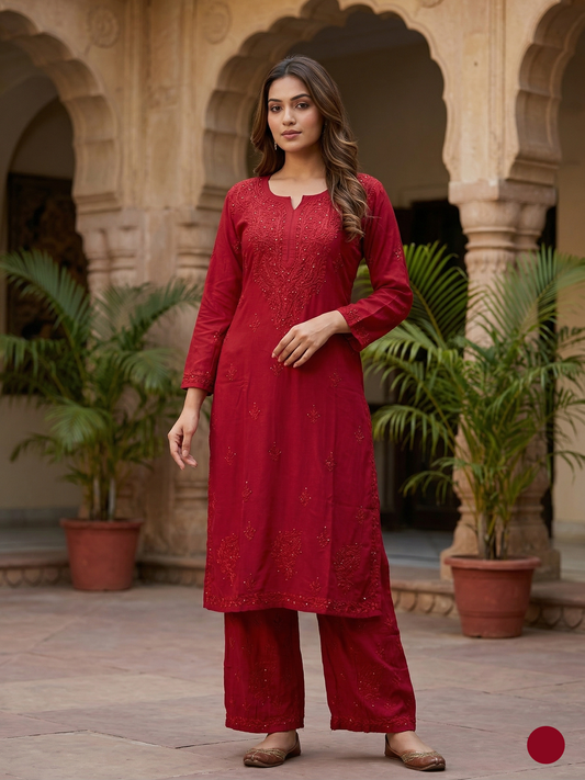 Woman in a red traditional outfit standing in an architectural setting with plants.