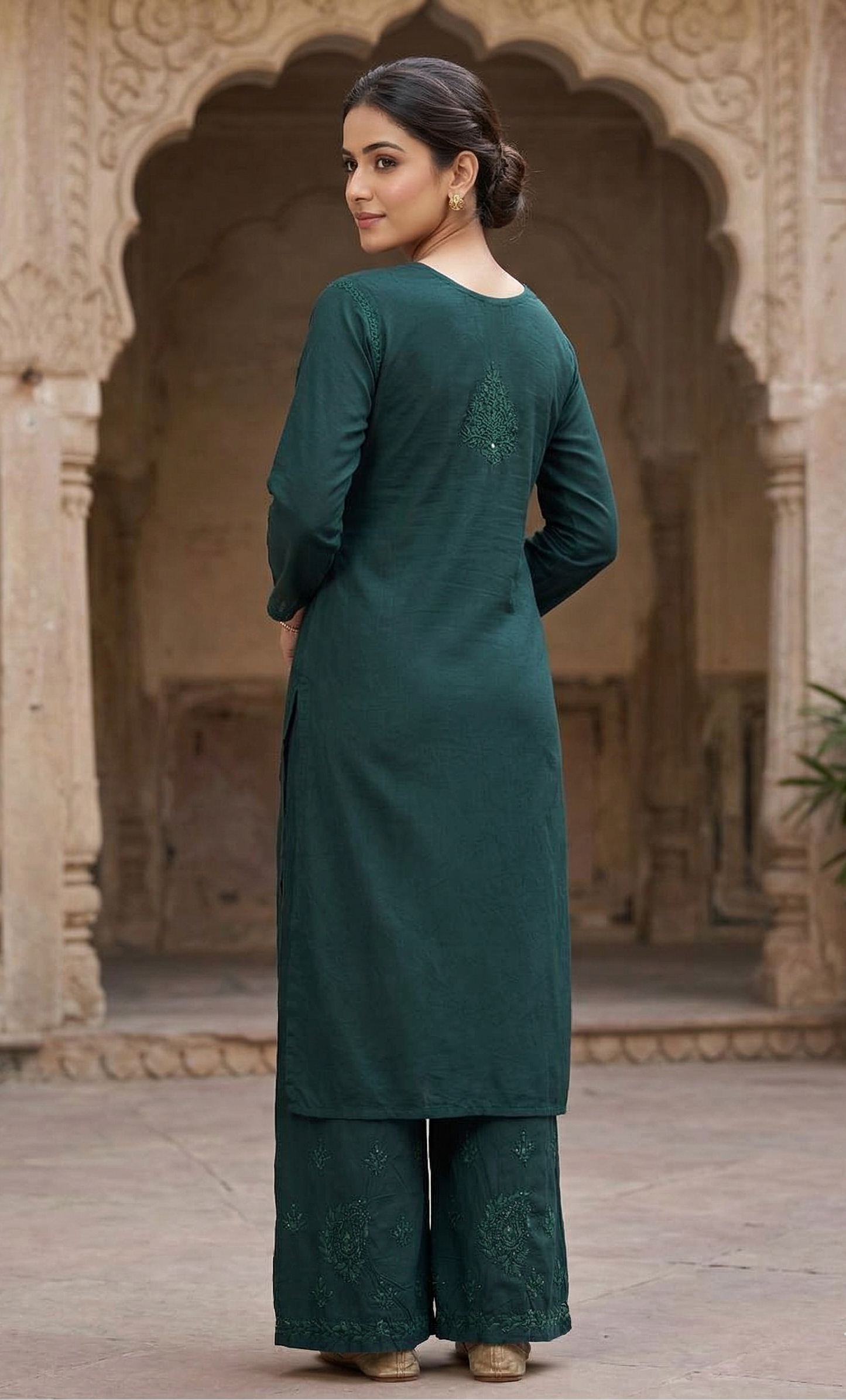 Woman in a teal traditional outfit standing in an architectural setting