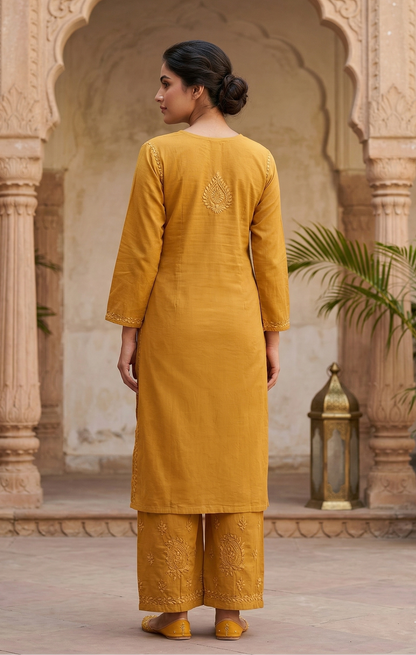 Woman in a mustard yellow traditional outfit standing in an ornate courtyard.