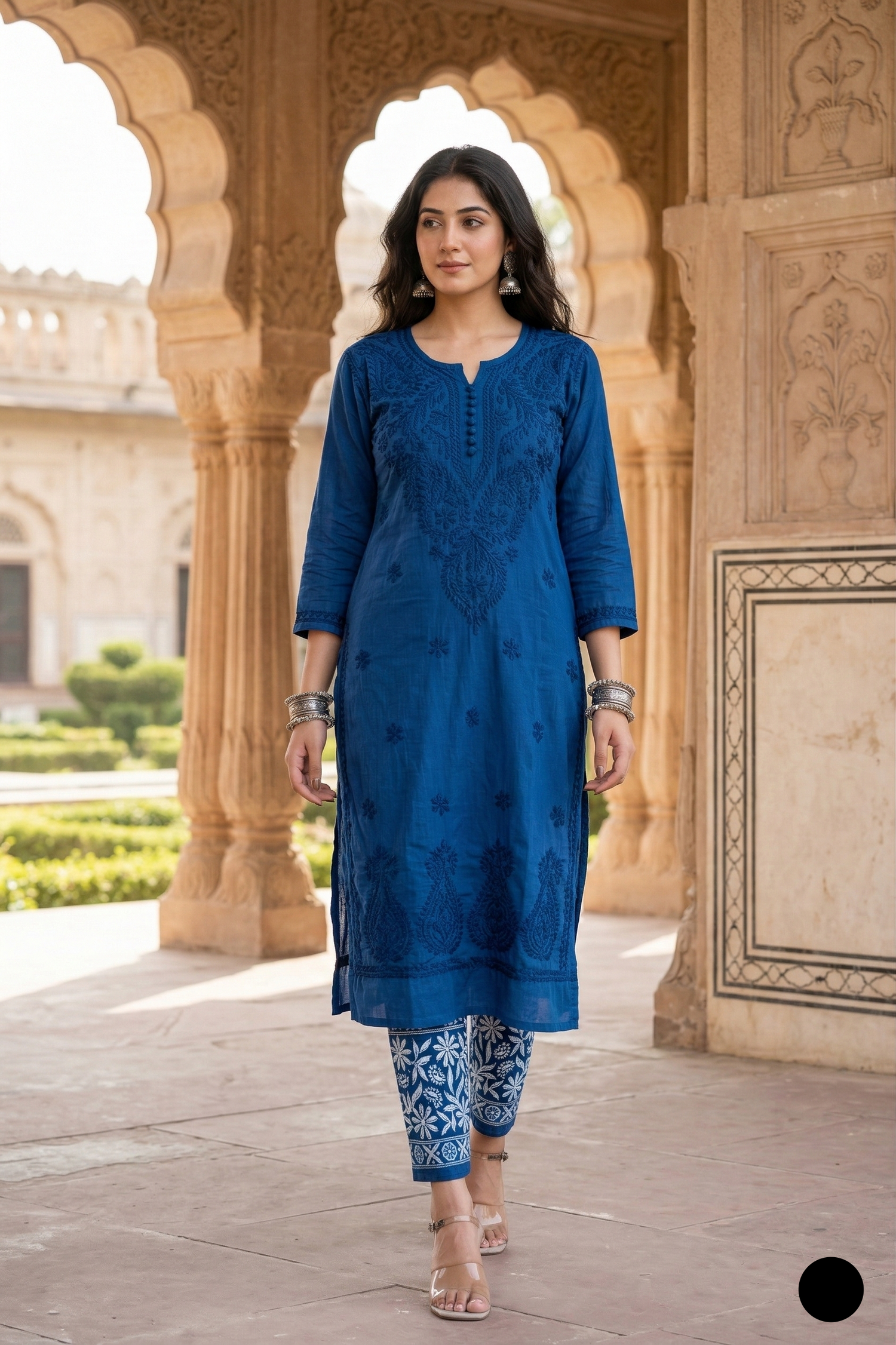 Woman in a blue traditional outfit standing in front of an architectural structure.